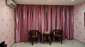 A room with pink curtains, two wooden chairs, a small table, and an air conditioning unit on the wall. - 168 Business Hotel (Jinjiang)