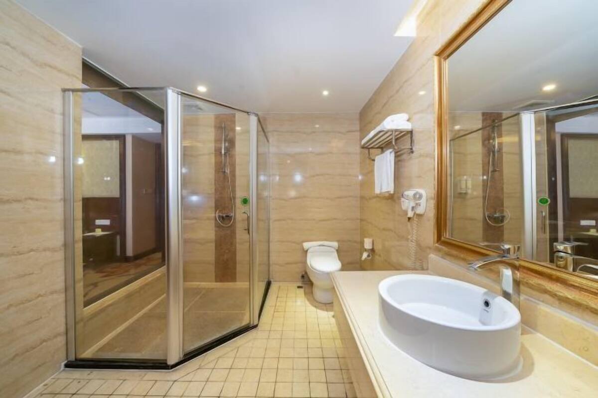 A modern bathroom with a glass-enclosed shower, a white sink, and a large mirror.