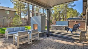 Un espacio al aire libre con patio, una chimenea de piedra, un sofá y un comedor.