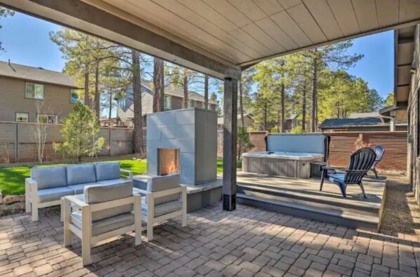 An outdoor patio area with a stone fireplace, a sofa, and a dining set.