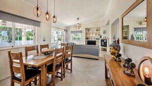 A modern interior with a dining area, a sofa, a TV, and decorative items. - Casa Celina (Guia)