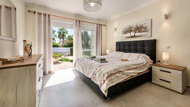 A bedroom with a bed, bedside tables, a window with curtains, a ceiling light fixture, and a painting on the wall. - Casa Celina (Guia)