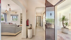 A modern interior with a sofa, a fire extinguisher, a potted plant, and a door leading to another room. - Casa Celina (Guia)