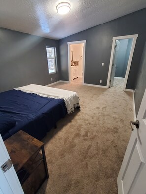 Cozy retreat with a large bed, nightstand, and window.