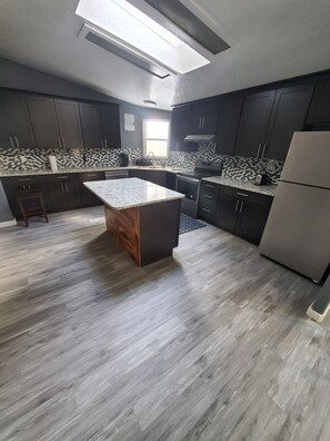 Enjoy cooking in this well-equipped kitchen with a central island, dark cabinetry, and oven.
