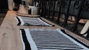 Un suelo de madera con un tapete a rayas blancas y negras.