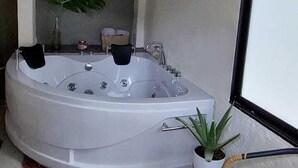 Un área de spa con un jacuzzi grande, una pequeña planta en maceta y una silla de mimbre.