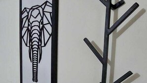 Una obra de arte colgada en la pared con un elefante y un perchero de metal negro.