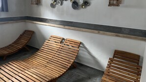 A spa room with wooden loungers, a decorative wall piece, and two wall-mounted lanterns. - House with wellness near ski slopes (Jesenice)