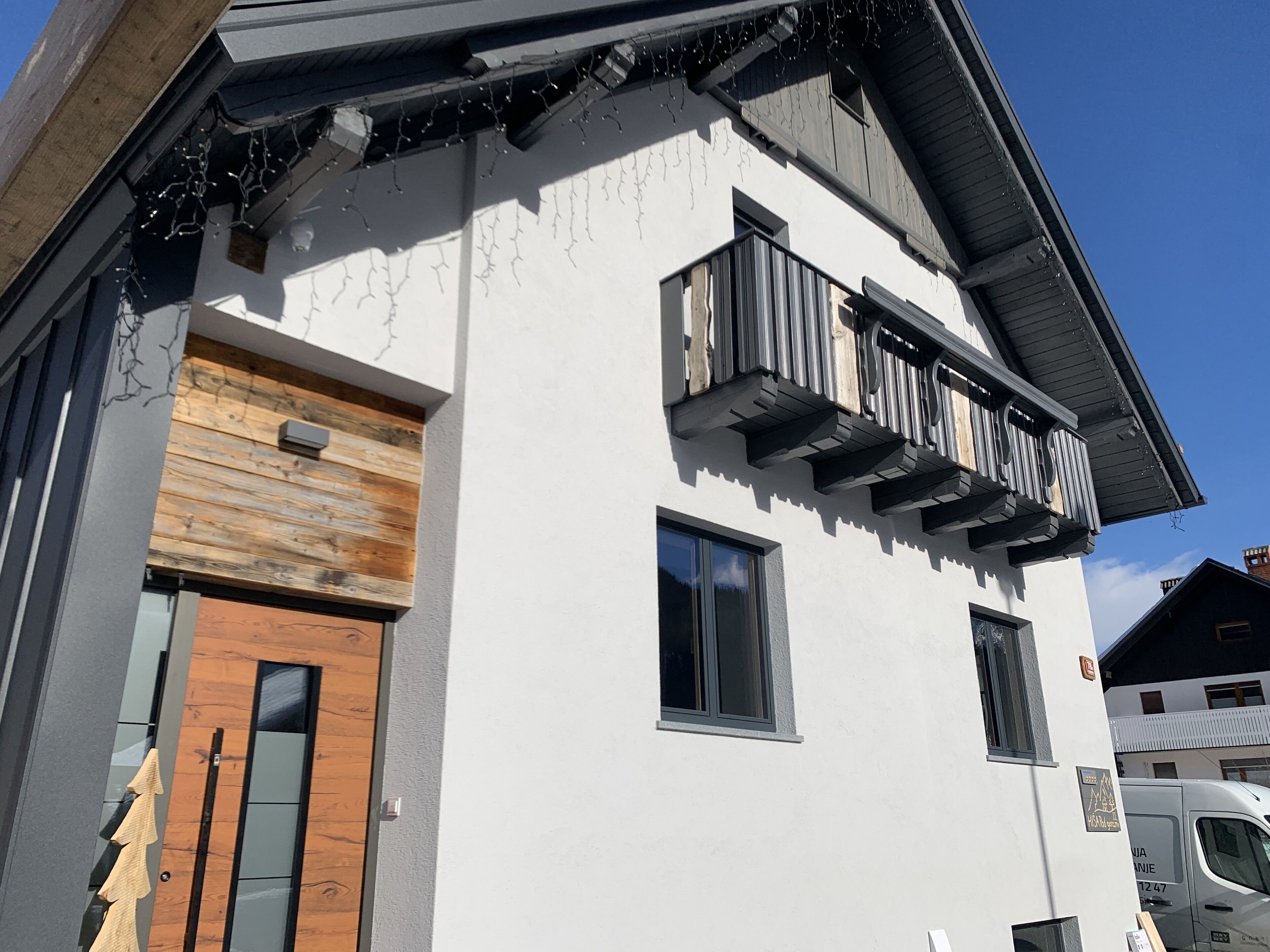 Un bâtiment à la façade blanche, doté d’une porte en bois et d’un balcon avec une rambarde en métal.