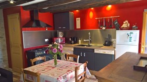 Una cocina con paredes rojas, electrodomésticos de acero inoxidable y una mesa de comedor decorada con un centro de mesa floral.