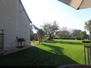 Un patio trasero bien cuidado con césped, una mesa de patio y una pérgola.