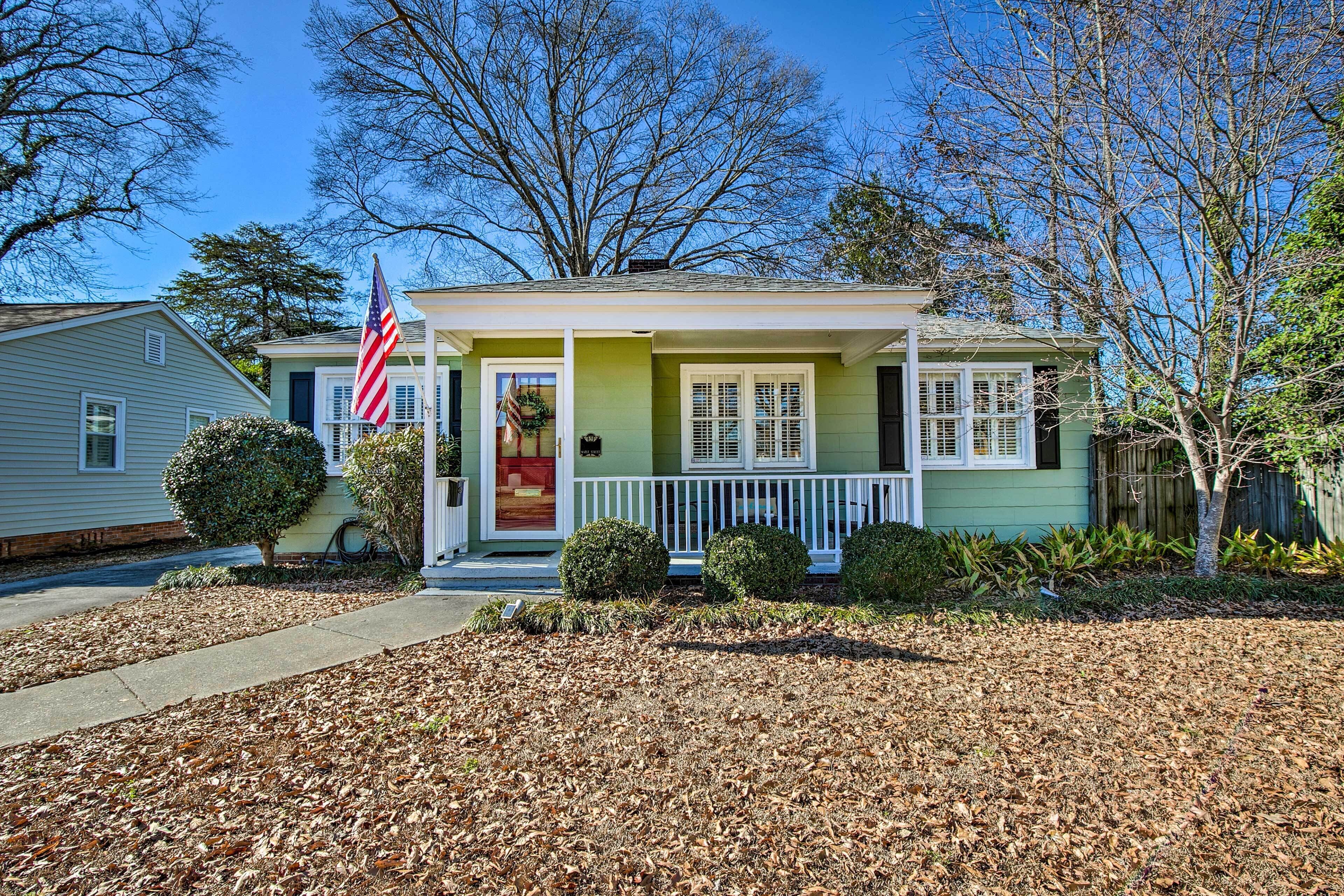 A single-story house with a front porch, a small front yard, and a flag.