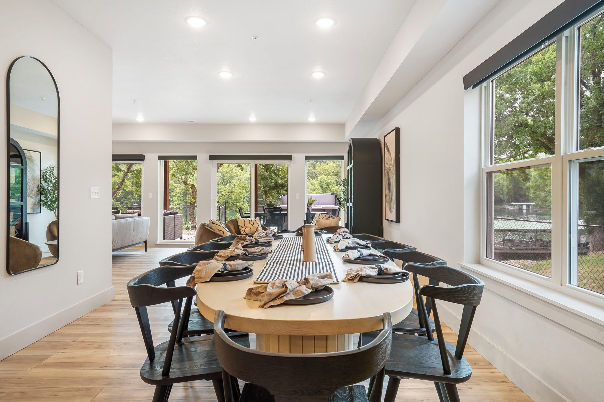 Un vaste espace dédié à la salle à manger, avec une grande table ronde, de nombreuses chaises et une vue sur l’extérieur grâce à de grandes fenêtres.