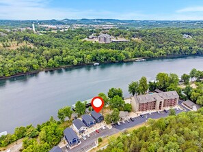 Vue aérienne d’une propriété située au bord d’un lac, avec un parking, des bâtiments et un marqueur rouge indiquant l’emplacement.