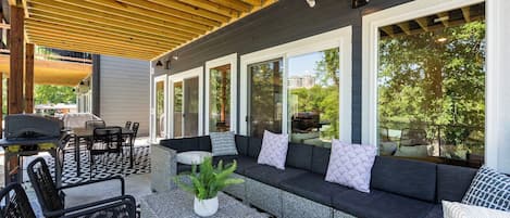 An outdoor patio with a covered seating area, a grill, and a dining table.