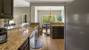 A modern kitchen with granite countertops, dark cabinetry, and a built-in dishwasher. - Renovated Cabin with Screened-In Porch, Life-Size Games, Community Pools & Free Tickets Near SDC (Reeds Spring)