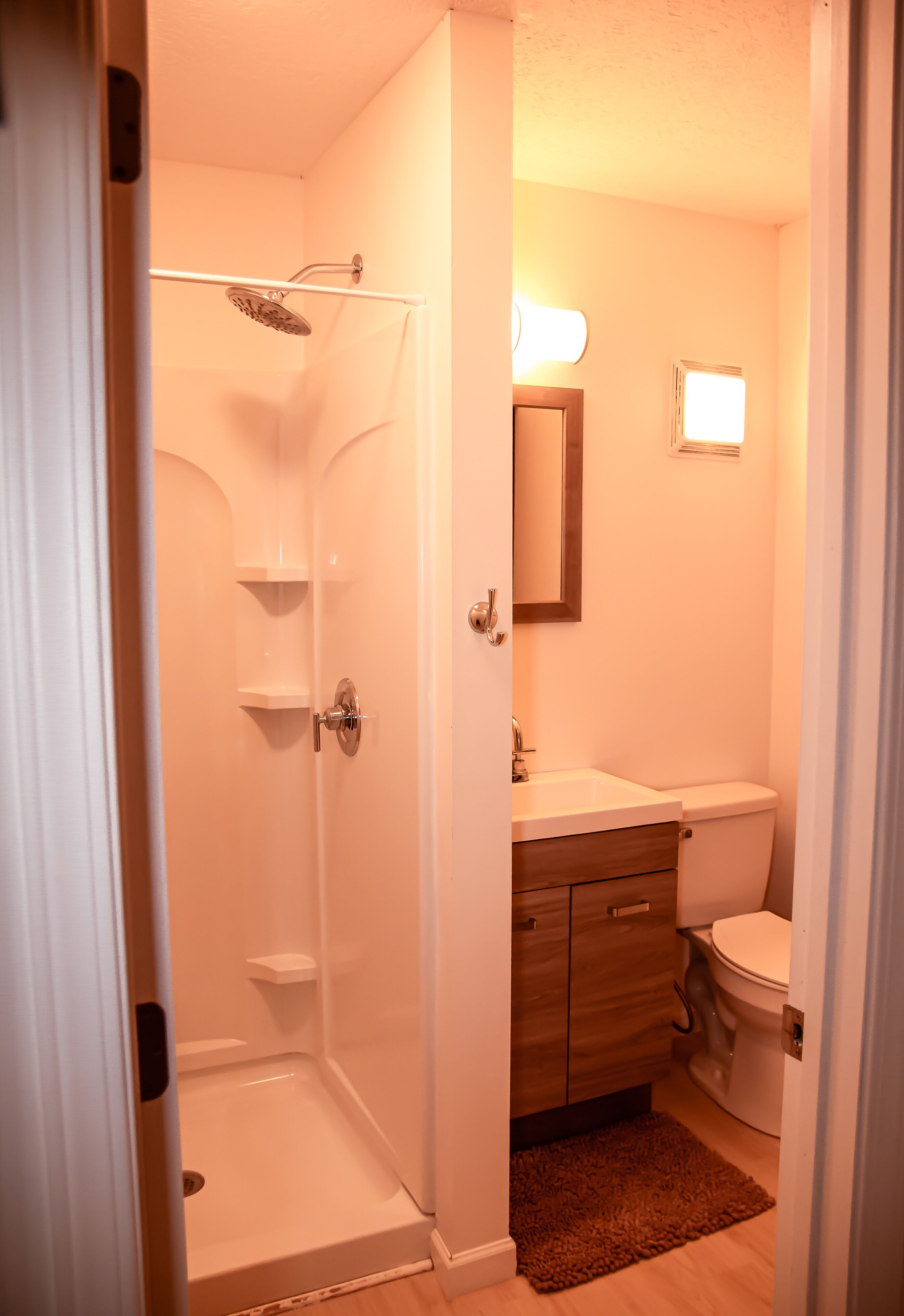 A bathroom with a shower, toilet, sink, and vanity.