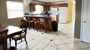 Une cuisine spacieuse dotée de meubles en bois, d’un îlot central et d’un coin repas avec une table et des chaises.