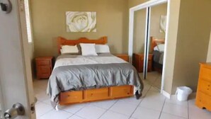 Une chambre à coucher avec un lit, une table de chevet, une commode et un miroir.