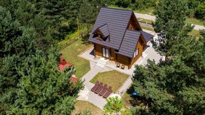 A wooden cabin with a sloped roof, surrounded by dense forest.