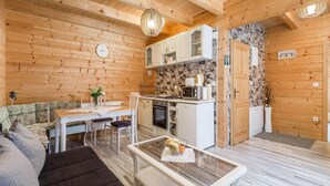 A cozy cabin interior with a dining area, kitchen, and a living room with a sofa and a coffee table.