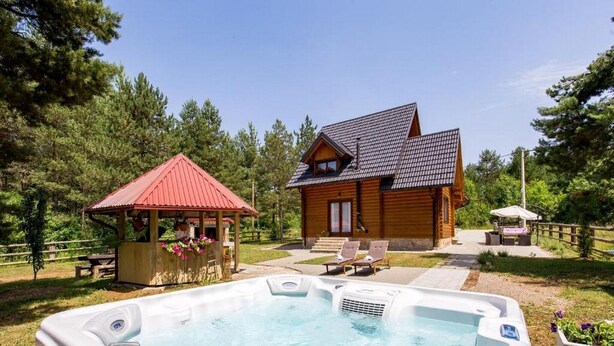 A hot tub in a backyard with a wooden house and a gazebo.