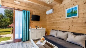 A cozy room with a wooden interior, a sofa, a coffee table, a TV, and a window with curtains.