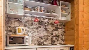 A compact kitchen with a stone backsplash, white cabinetry, and a microwave. - Apartments Plitvice forest - One Bedroom Apartment with Terrace (Plitvicka Jezera)