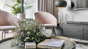 Un salon moderne avec une table basse ronde, une plante en pot, un livre, une bougie et une lampe.
