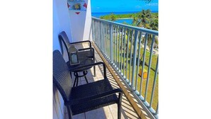 Uma varanda com mesa e cadeiras, vista para o oceano e uma placa com a inscrição 'View from the balcony!'