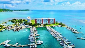 Marina com vários barcos atracados, um grande edifício de hotel e uma vista ampla da água e do céu ao redor.