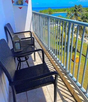 A balcony with a table and chairs, a view of the ocean, and a sign that reads "View from the balcony!"