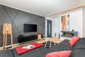 Relax in this stylish living room with a large flat-screen TV, comfortable sofa, and cozy fireplace.