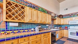 A kitchen with wooden cabinets, a wine rack, and colorful tile backsplash. - Vacation Getaway Steps from the Water! (Choya Bay)