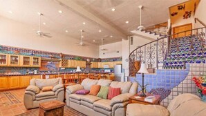 A spacious living area with a sofa set, a coffee table, and a patterned rug. A staircase with a decorative railing leads to an upper level. - Vacation Getaway Steps from the Water! (Choya Bay)