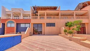 A two-story building with a covered balcony and a paved courtyard. - Vacation Getaway Steps from the Water! (Choya Bay)
