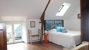 A bedroom with a skylight, a bed, a chair, and a small table. - Beautiful Traditional Breton House in the Forest (Meslan)