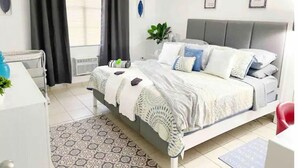 A modern bedroom with a bed, bedside tables, a desk, and a window with curtains. - Casa PIÑA, 3 bedroom condo & gated area (Fajardo)