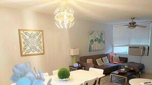 A dining area with a round table, chairs, a decorative green topiary, and a chandelier. - Lovely 3 bedroom condo with pools & gated area. (Fajardo)