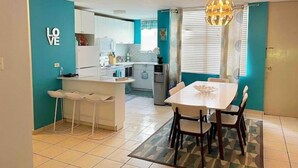 A modern kitchen with a central island, white cabinets, and a dining area with a table and chairs. - Lovely 3 bedroom condo with pools & gated area. (Fajardo)