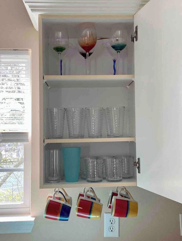A cabinet with wine glasses and cups.
