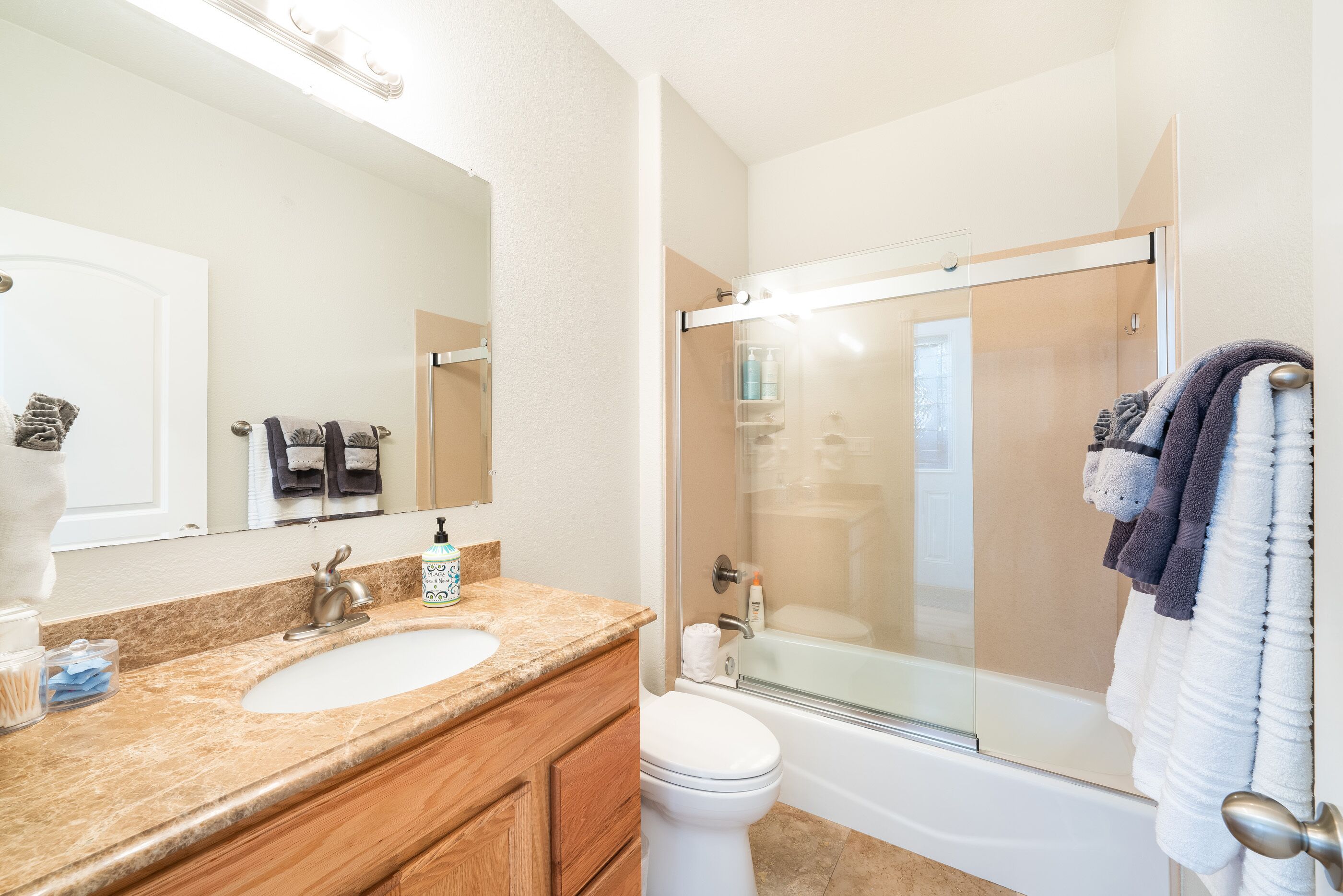 A bathroom with a sink, mirror, toilet, and shower.