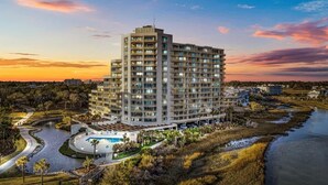 A multi-story hotel with a pool, surrounded by a landscaped area and a river. - Oceanfront 11th-Floor End Unit | Quiet & Private | Walk to Barefoot Landing (Myrtle Beach)