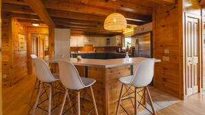 L’intérieur d’un chalet en bois comprend une cuisine, un coin repas et un bar avec des sièges.