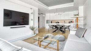 A modern living room with a flat-screen TV, a glass coffee table, and a sofa. - Kallirrois 89 Suite (Athens)