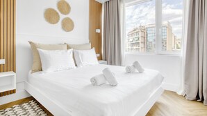 A modern hotel room with a large bed, a view of the city, and a wooden accent wall. - Kallirrois 89 Suite (Athens)