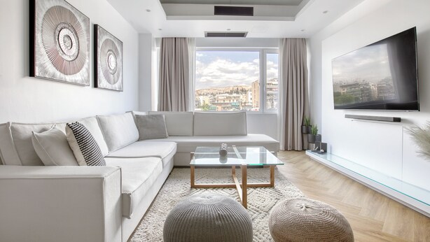 A modern living room with a sofa, glass coffee table, and a flat-screen TV. - Kallirrois 89 Suite (Athens)