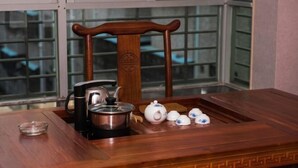 A wooden table with a teapot, cups, and a kettle. - Jinxin Yixiang Hotel (Meizhou)