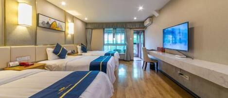 A hotel room with three beds, a desk, a TV, and a window with curtains.